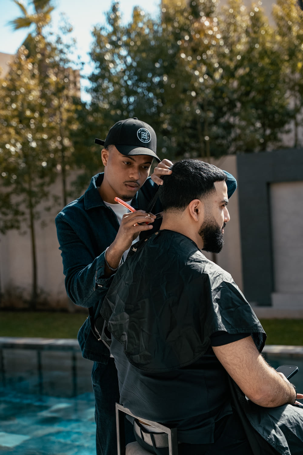 Kapper van PrimeTime Barbershop knipt George Karapetjan bij het zwembad in Marrakech