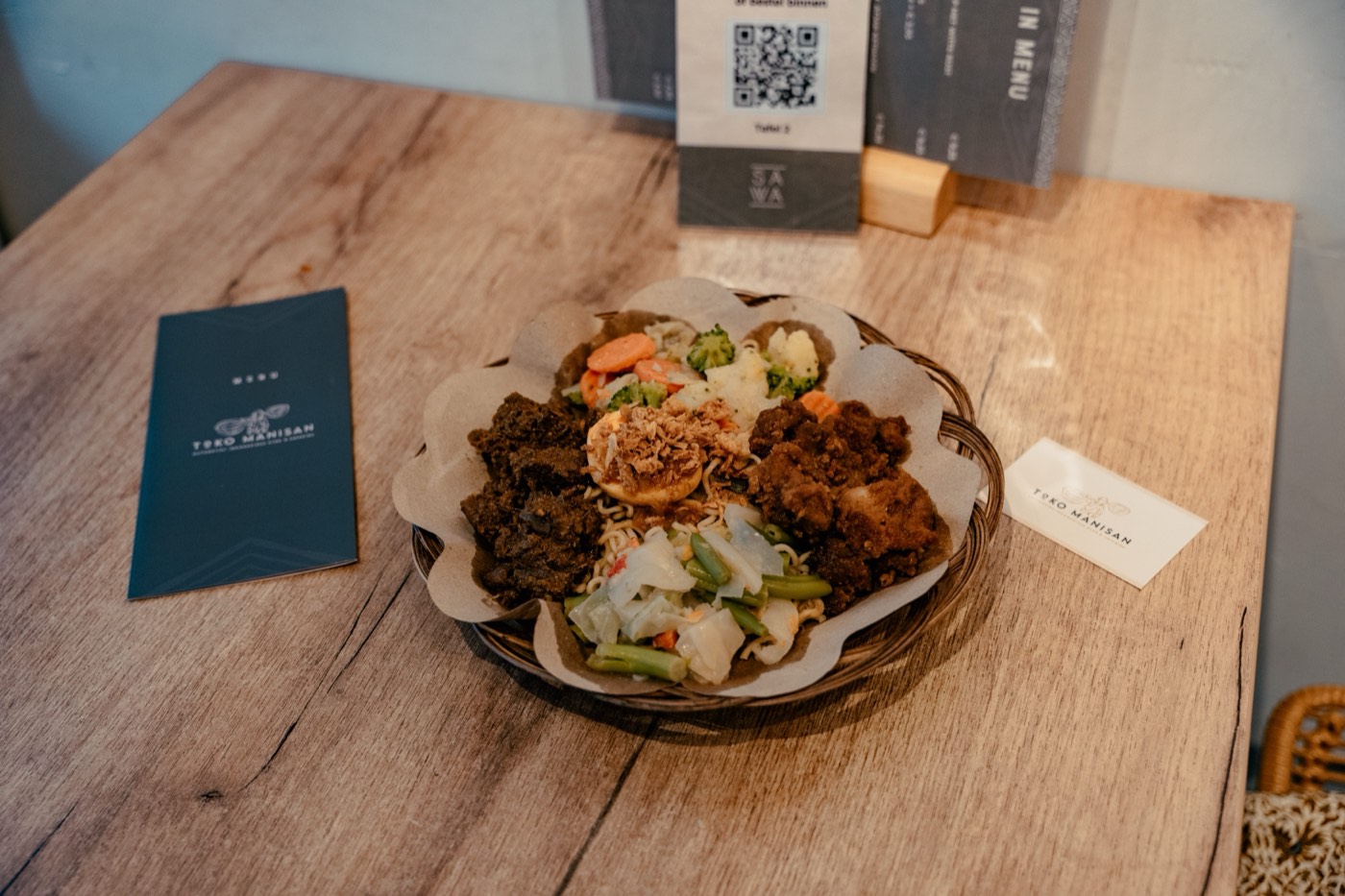 Een complete maaltijd van Toko Manisan met menukaart op tafel